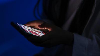 Frau im Dunkeln hält ein Handy.