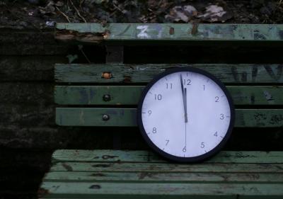Eine Uhr steht auf einer kaputten Bank