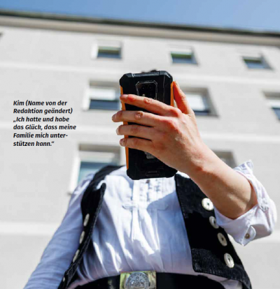 Eine von schräg unten aufgenommene Person blickt auf ihr Handy