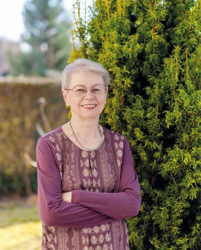 Klara steht neben einer Hecke