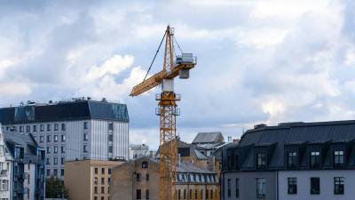 Baukran zwischen Häusern vor wolkigem Himmel Baukran zwischen Häusern vor wolkigem Himmel