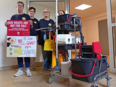 Vier Kolleginnnen aus der Gebäudereinigung neben einem Wagen mit Reinigungsmitteln.