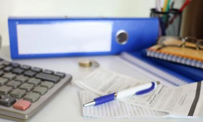 Aktenordner, Taschenrechner und Papiere auf einem Schreibtisch Aktenordner, Taschenrechner und Papiere auf einem Schreibtisch