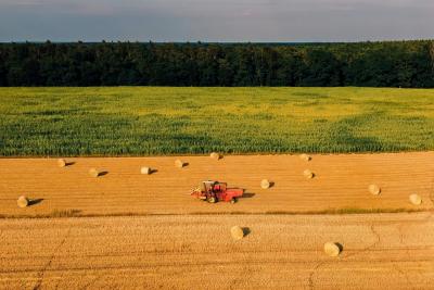 Ein Feld mit Erntefahrzeug und Heuballen Ein Feld mit Erntefahrzeug und Heuballen