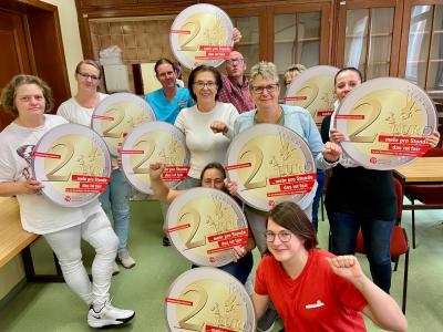 Gruppenfoto der Beschäftigten mit großen 2-Euro-Münzen aus Papier