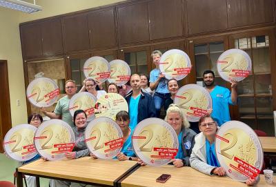 Gruppenfoto der Beschäftigten mit großen 2-Euro-Münzen aus Papier
