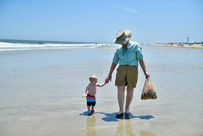 Ein älterer Mann und ein Kind gehen am Strand spazieren Ein älterer Mann und ein Kind gehen am Strand spazieren